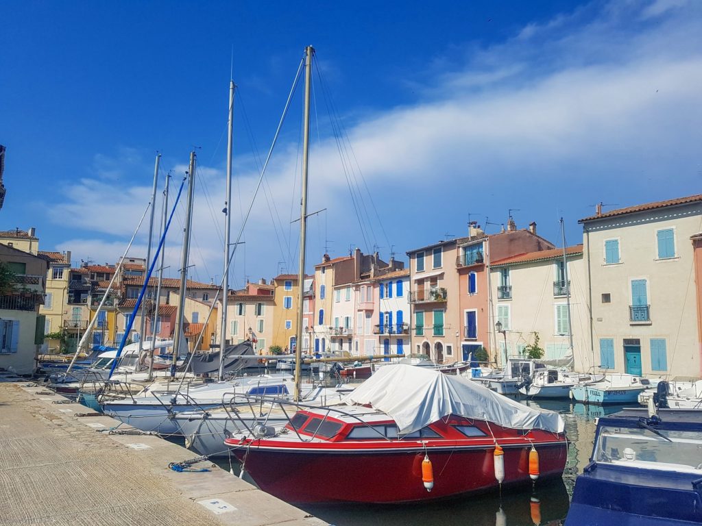 The houses of Martigues Harbour show off their bright colours. The masks of small boats reach up to the clouds.