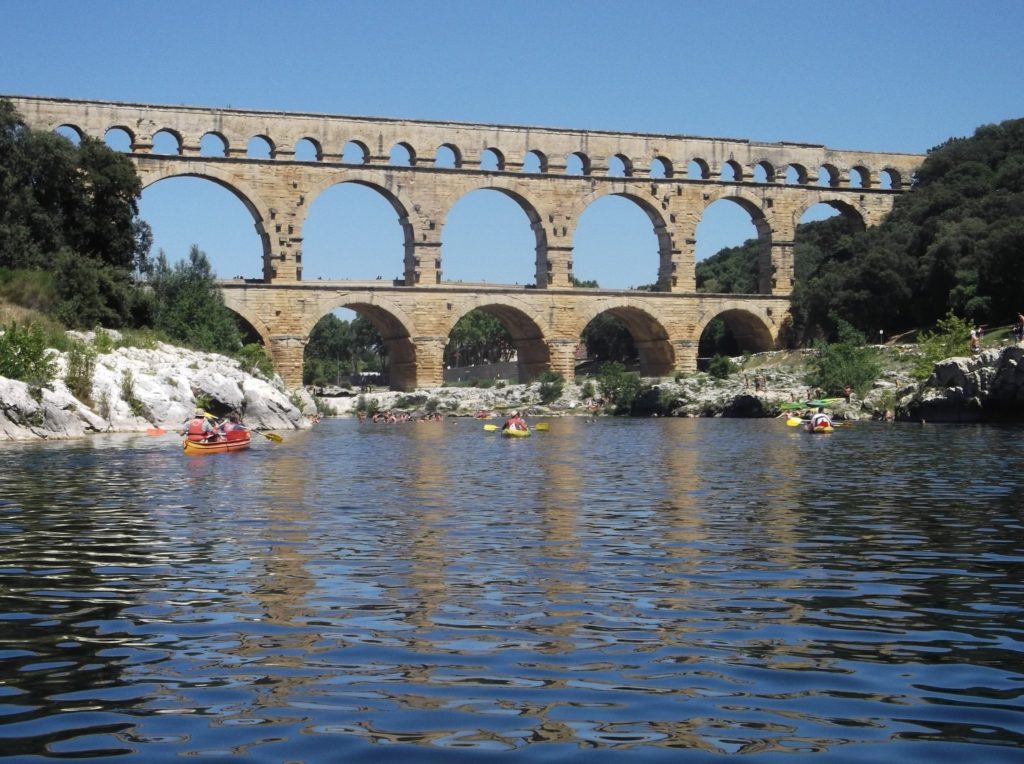 Canoes and kayaks cruise under an impressive bridge.