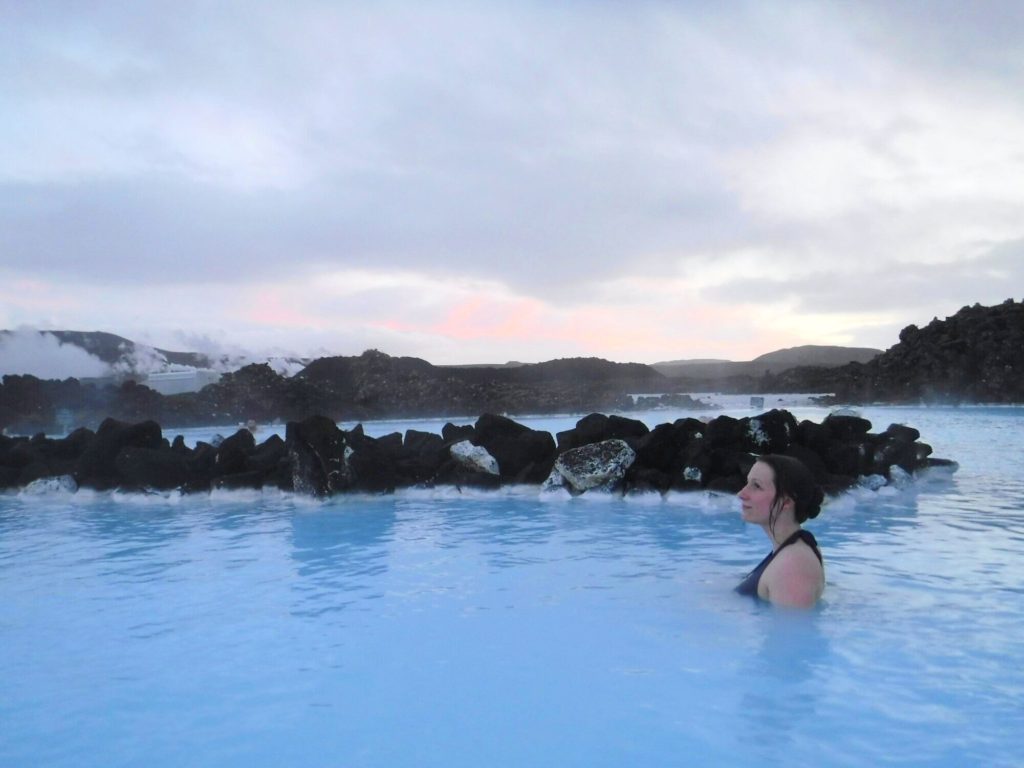 A girl relaxing in the milky waters of the Blue Lagoon looks up at the sky.