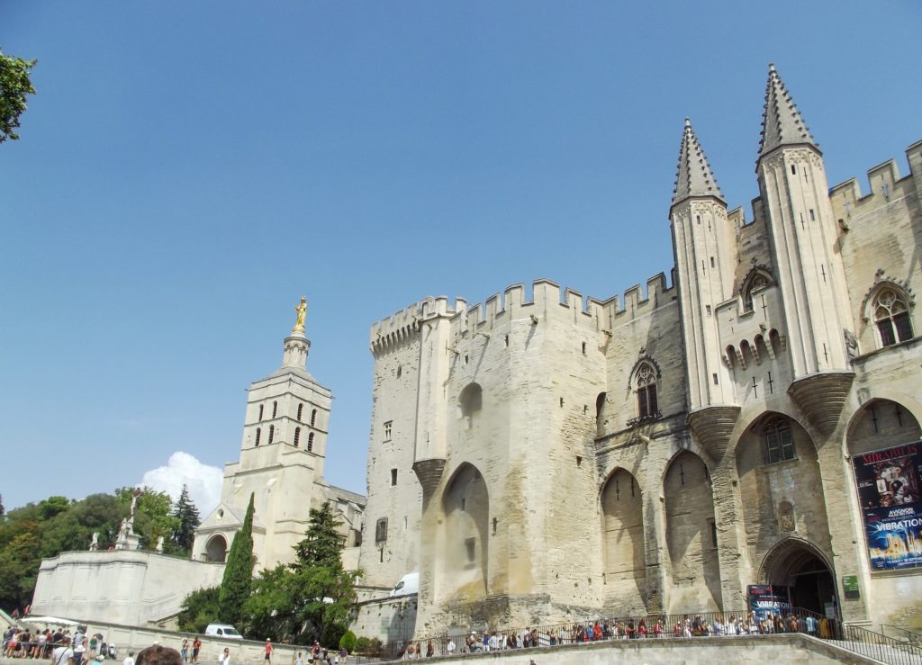 The impressive facade of the Palais de Papes. Tall spires and a tall entrance way.