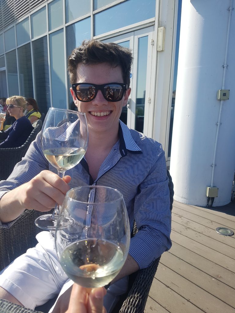 A boy sits in the sun with his wine.