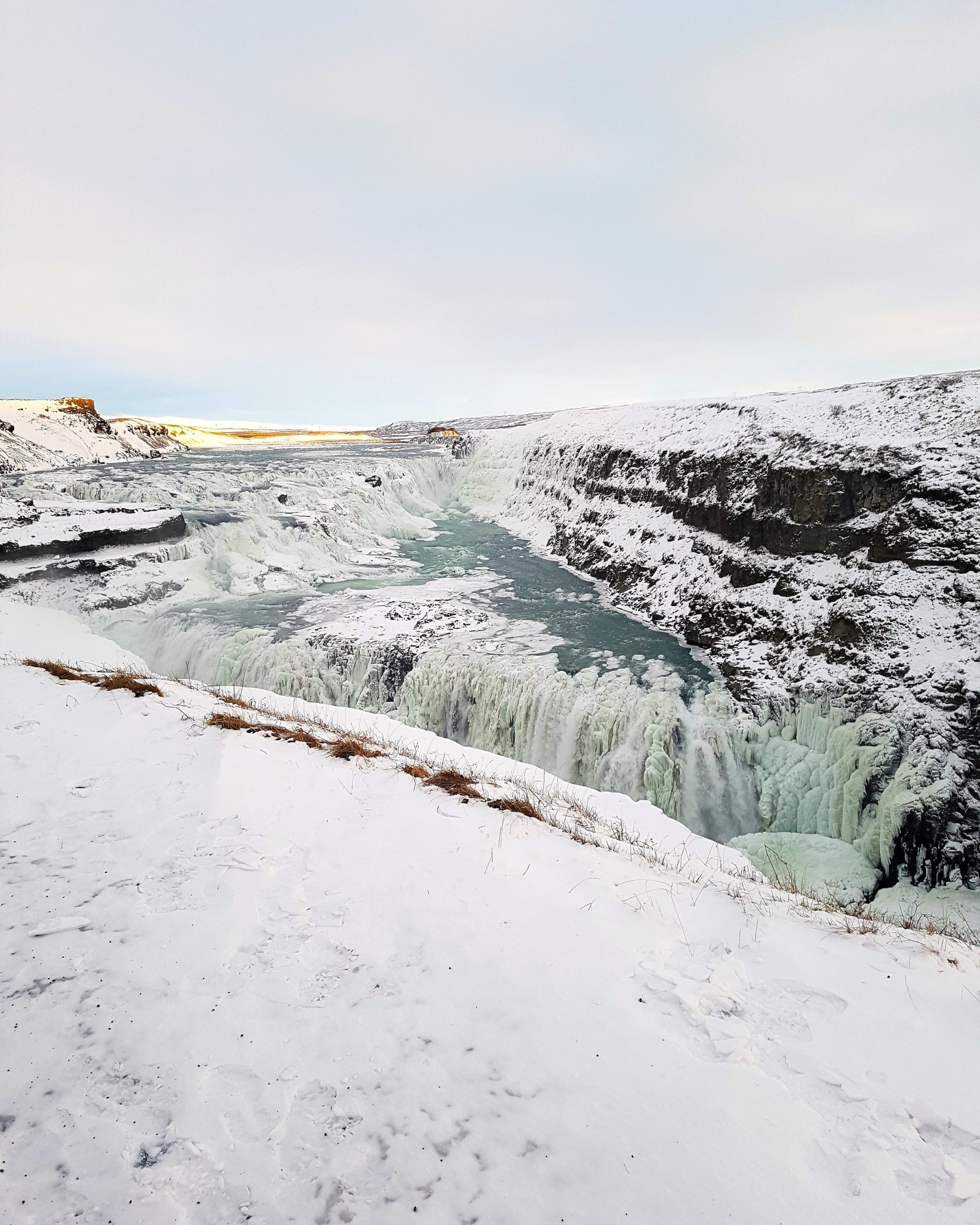 The frozen waters of Gullfoss shine in the golden light of sunset.