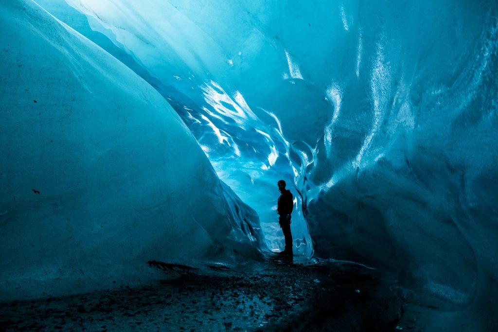 A man stands in the ice caverns of Vatnajökull National Park.