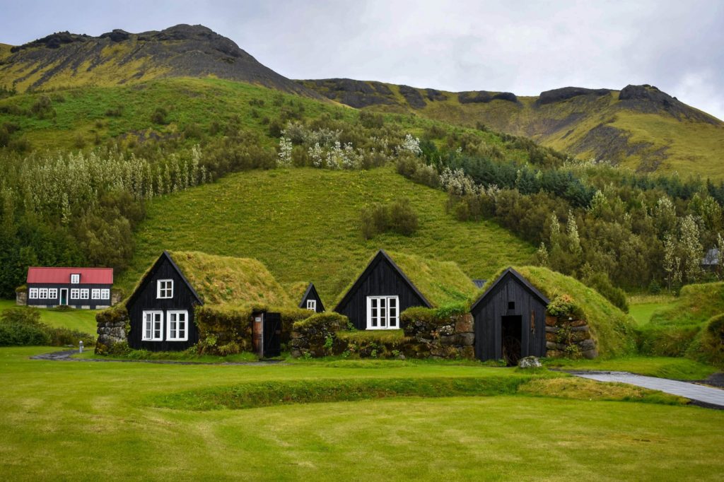 Turf-covered houses that blend into the green countryside, similar to those at Árbær Open Air Museum.