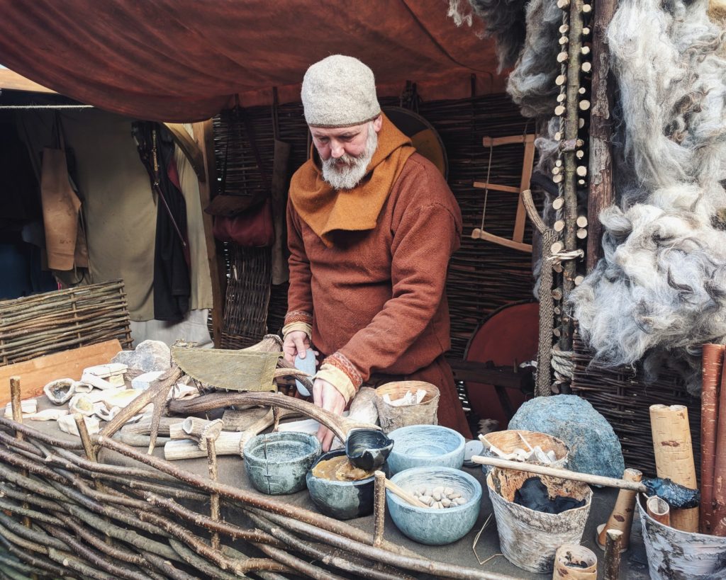 A man dressed as a Viking with his traditional tools and bowls.