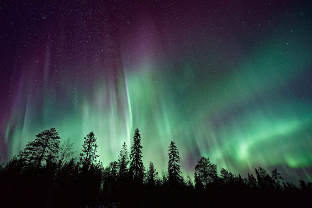The green and purple lights of the aurora borealis dance in the sky.