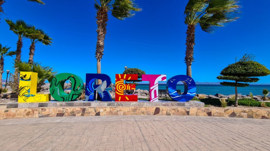 Neon coloured letters spell out Loreto on the seafront