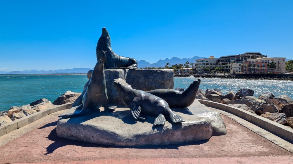 A metal sculpture in Loreto, Mexico: four sea lions relax on rocks in the sunshine.