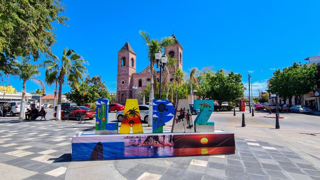 The La Paz sign in the central square is very colourful and sits in front of the Catedral de Nuestra Senora de La Paz - tall stone cathedral.