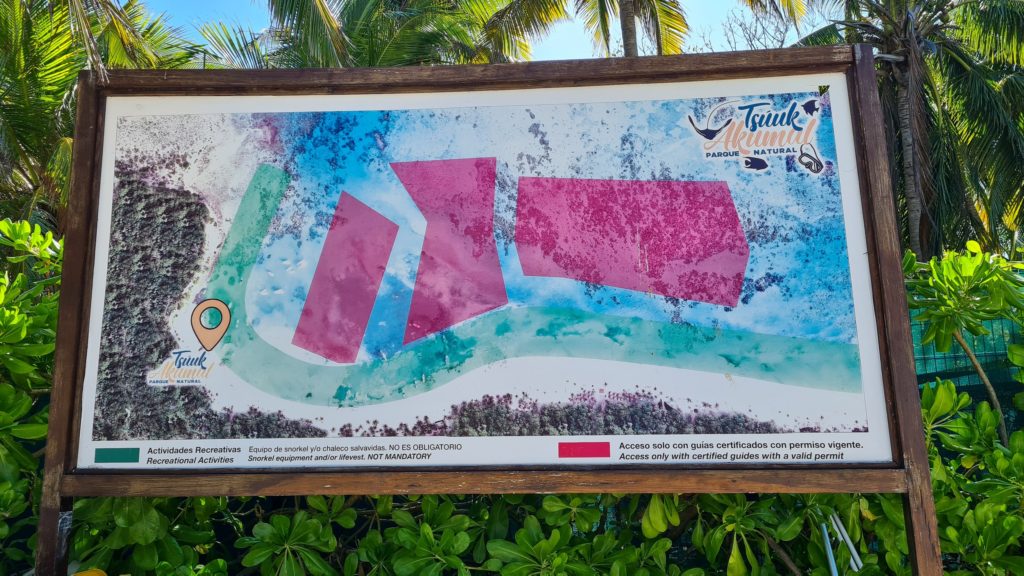 A sign shows the zones allowed for swimming in Akumal bay.