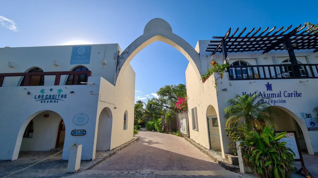 A rounded arch opens up to a sunny walkway. This is the entrance to Akumal.