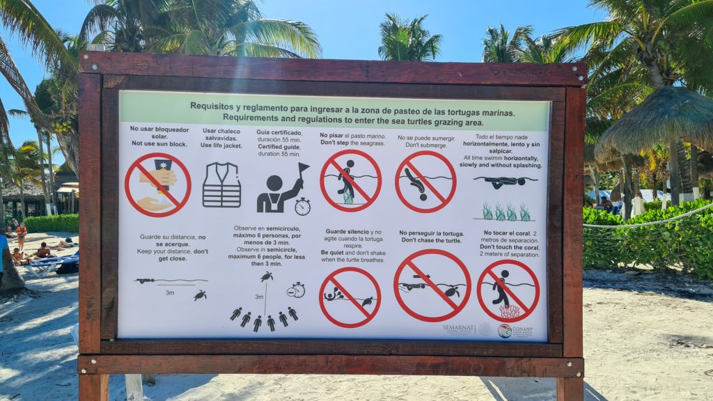 A sign depicts some of the rules and regulations of Akumal bay.