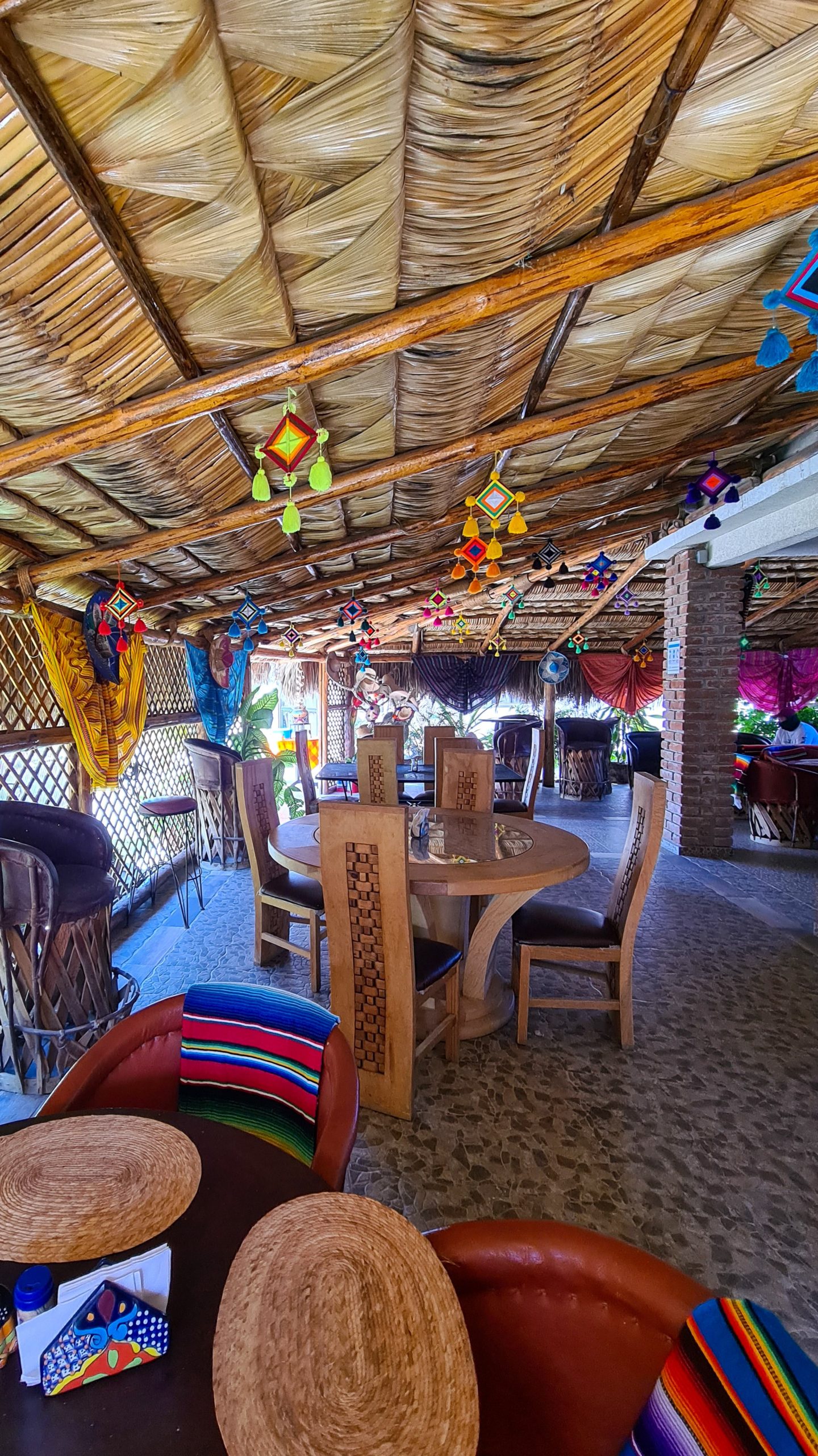 A colourful restaurant with a traditional palapa (palm leaf) roof.