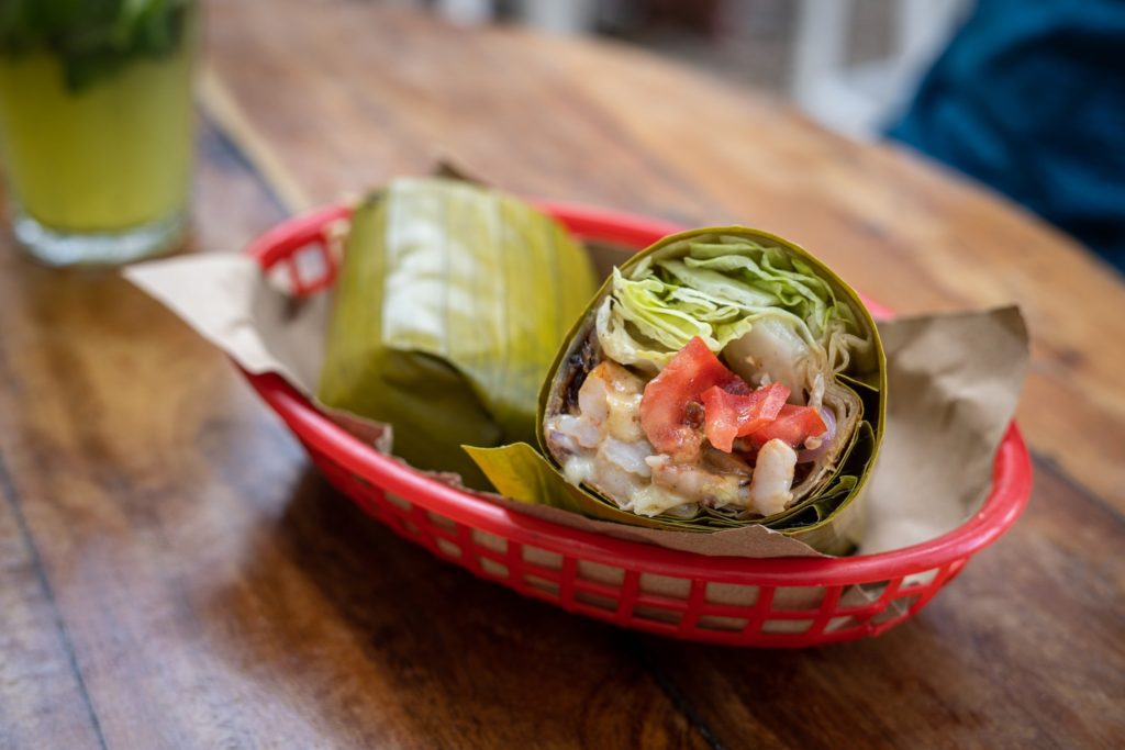 A tasty burrito wrapped in banana leaves.