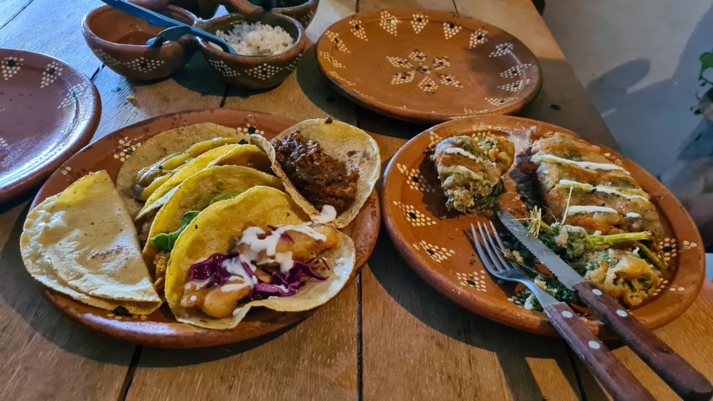 Tacos and deep-fried vegetables on traditional clay plates.