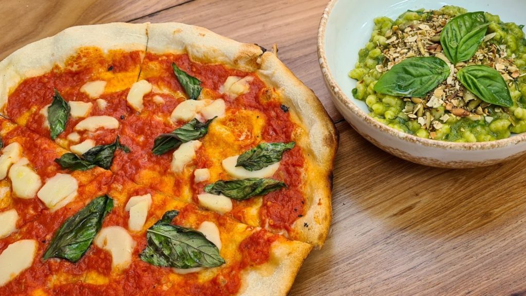 A vegan pizza and green pesto pasta.