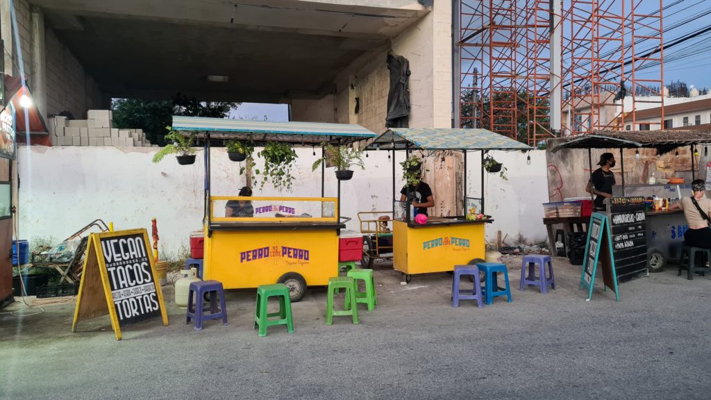 Street food stands painted yellow and the words "Perro no come Perro" can be seen on them.