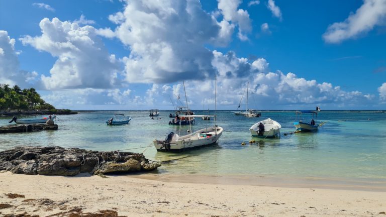Two lines of boats stretch out from the beach and into the ocean.