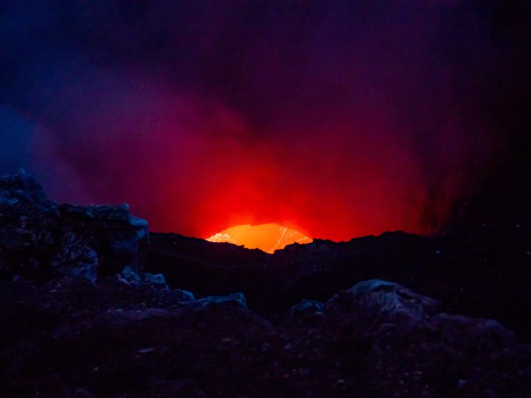 Waves and bubbles of lava can be seen inside a glowing red crater.