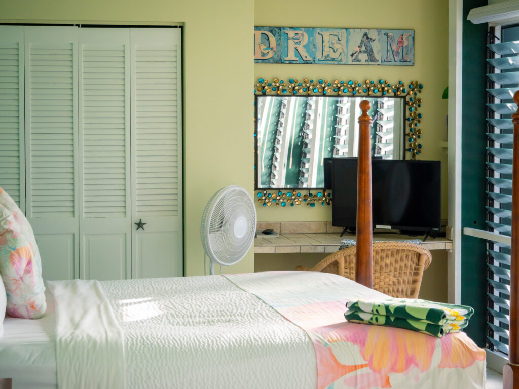 We see a vanity with a large mirror and a wicker chair. In the mirror, the Jalousie windows are clearly visible.