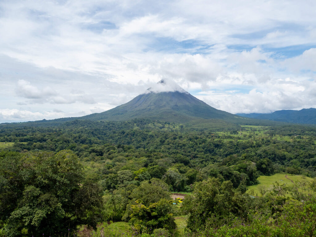 Arenal Volcano at a distance as it pierces the passing clouds.