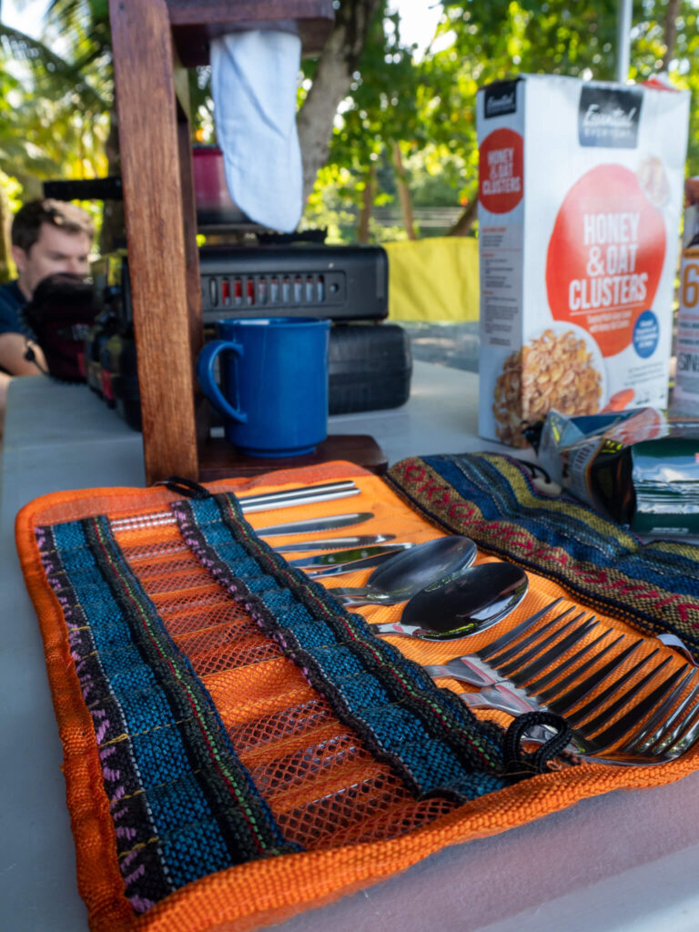 A selection of cutlery lined up neatly in a camping case. Dan is looking on from the side.