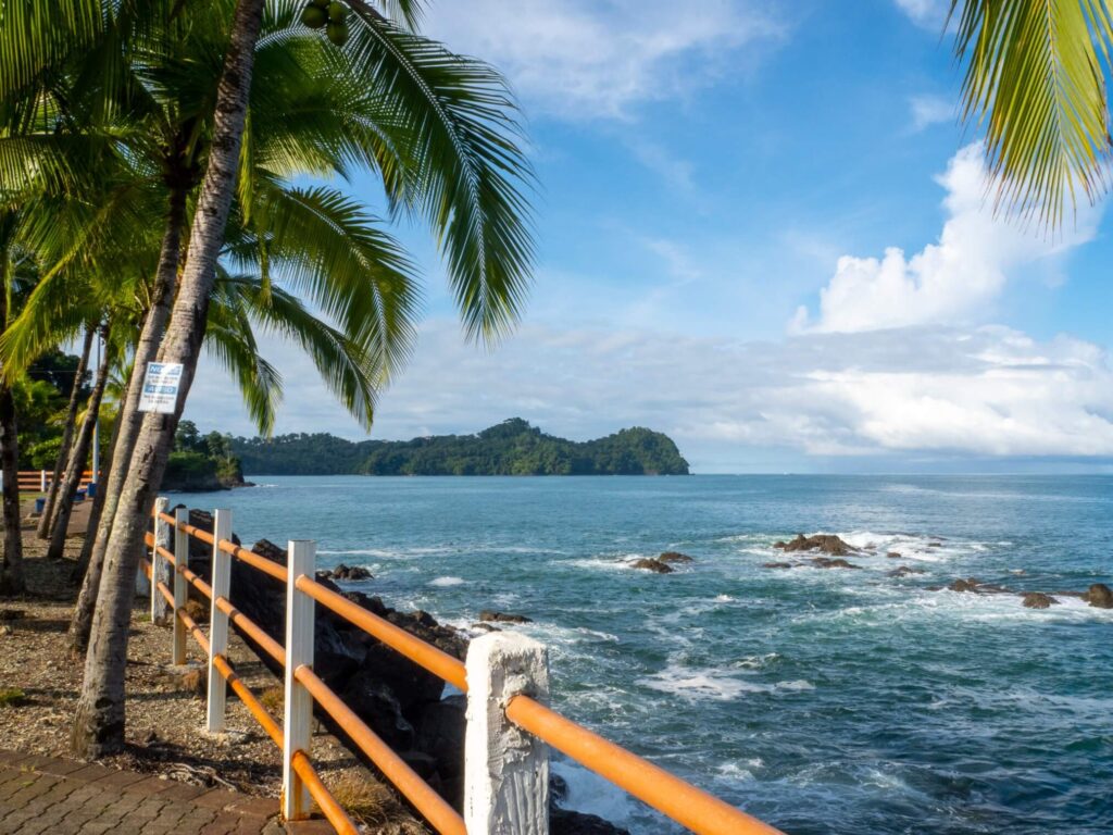 Looking past and fence out to sea at a forest-covered peninsula.