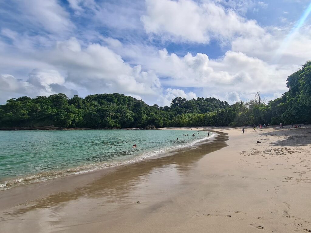 The sun shining on the curving sand of Manuel Antonio Beach.
