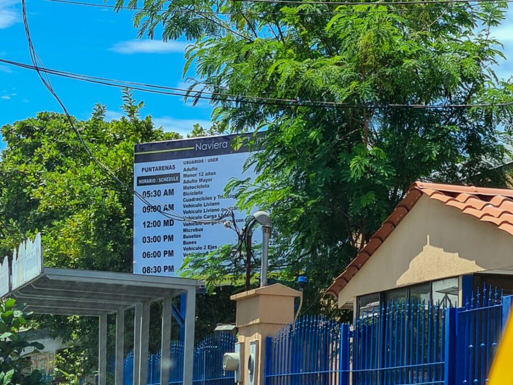 The Puntarenas ferry schedule displayed on a large board outside the terminal.