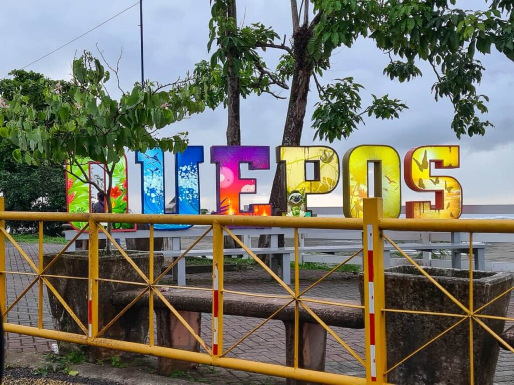 A multicoloured sign reading "Quepos".