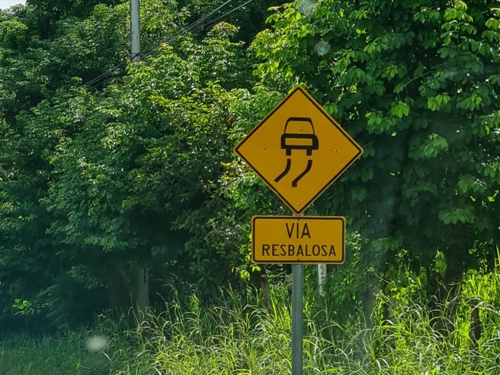 A road sign reads "via resbalosa" meaning "slippery road".