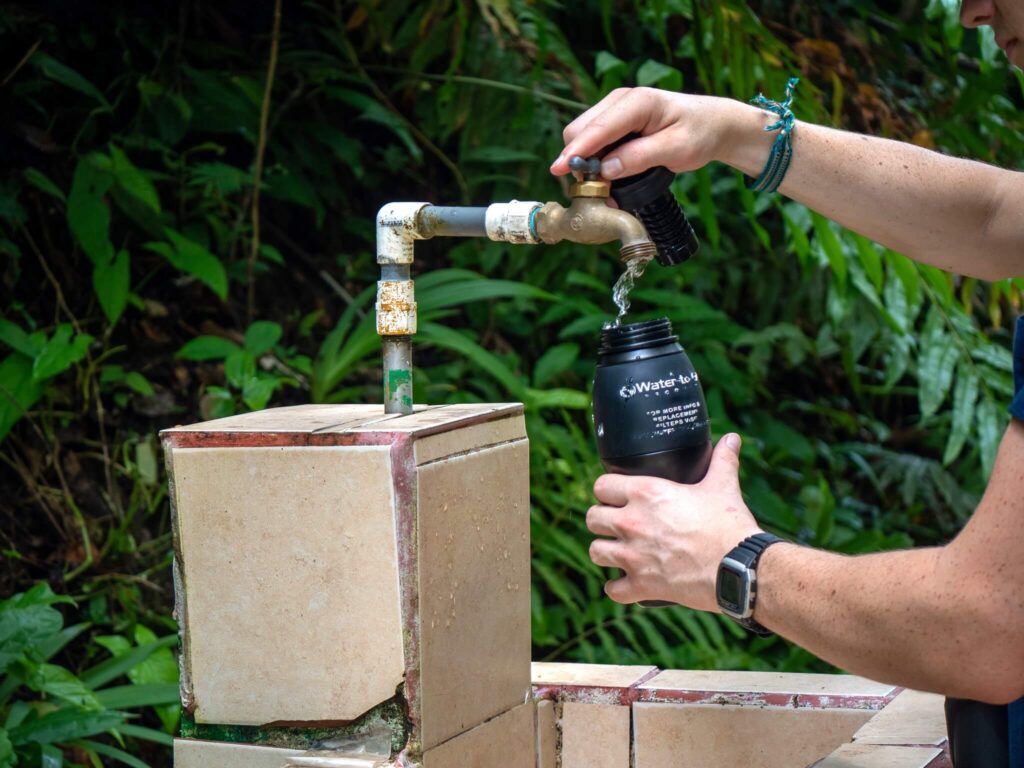 Filling up a Water-to-Go bottle from an outside water tap in a forest.