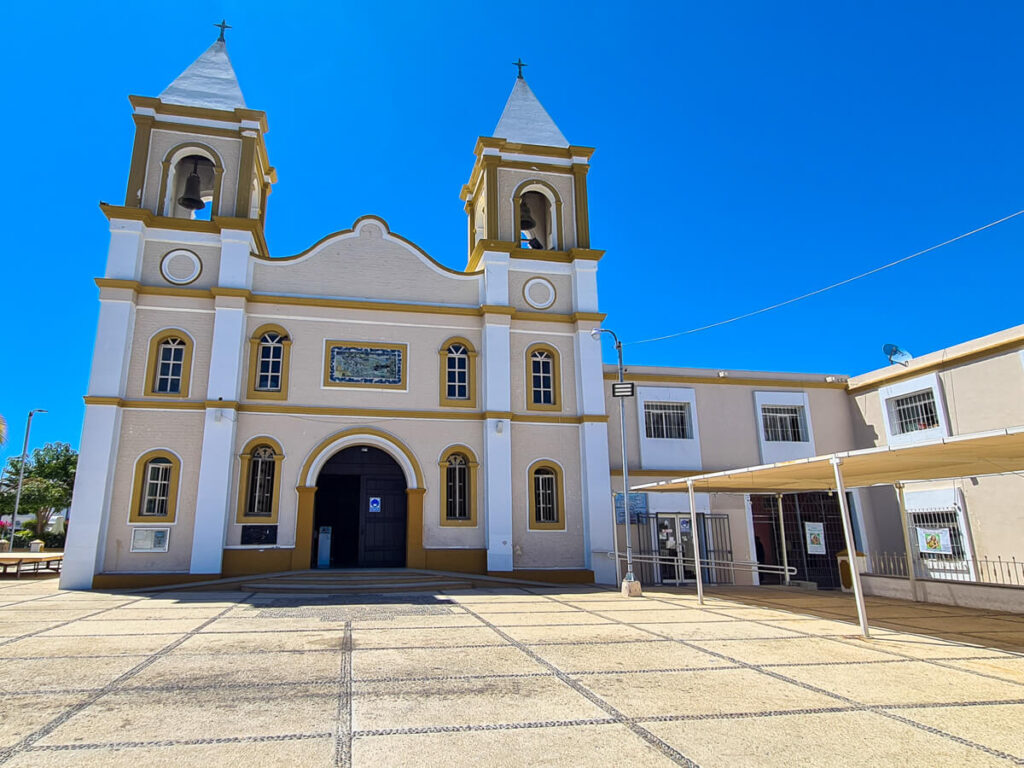 The Cathedral of San José del Cabo on a cloudless day. There are two small bell towers with Christian crosses on their roofs.