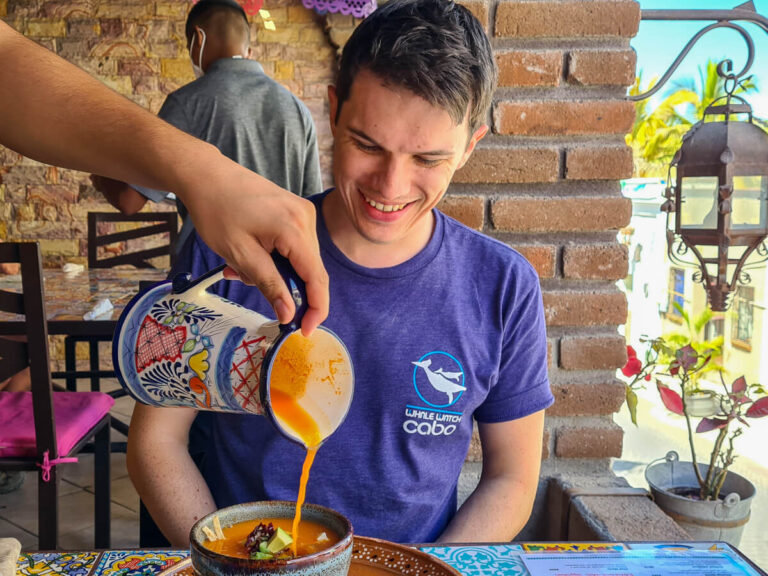 Dan smiling as a waiter pours Aztec Soup into a bowl in front of him.