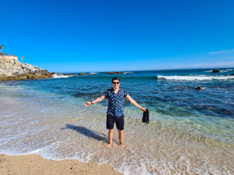 Dan standing in the shallows of Monumentos Beach with his arms out.
