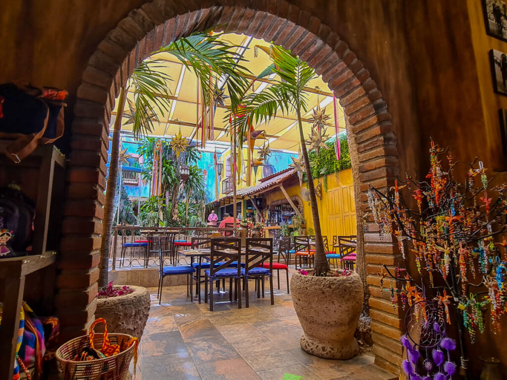 A colourful restaurant in San José del Cabo with potted plants, handmade decorations, and tables and chairs.