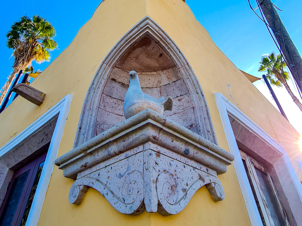 A stone sculpture of a dove, carved into the corner of a building.