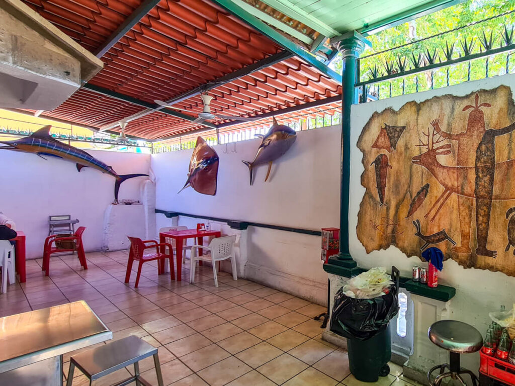 Inside the small El Estadio restaurant in La Paz, Mexico. There are painted models of fish on the walls as well as a painting of different animals.