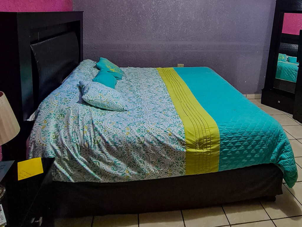A small hotel room in Hotel Isabela, San Carlos. The bed covers are bright aquamarine and green colours.