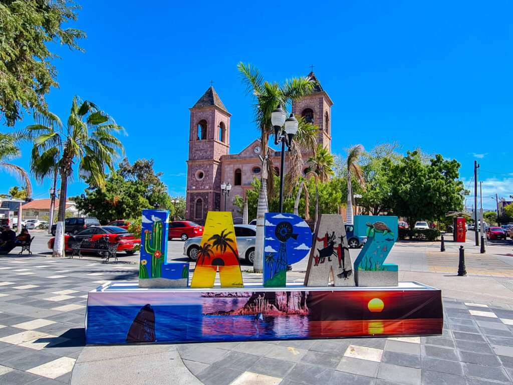 The painted La Paz, Mexico sign in the centre of town sits in front of Nuestra Señora de la Paz Cathedra. Each letter of the sign has a different image painted on it, representing different elements of La Paz.