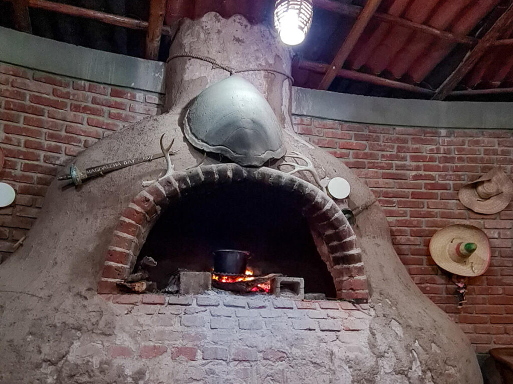 A large stone fireplace with a cooking pot resting in it.