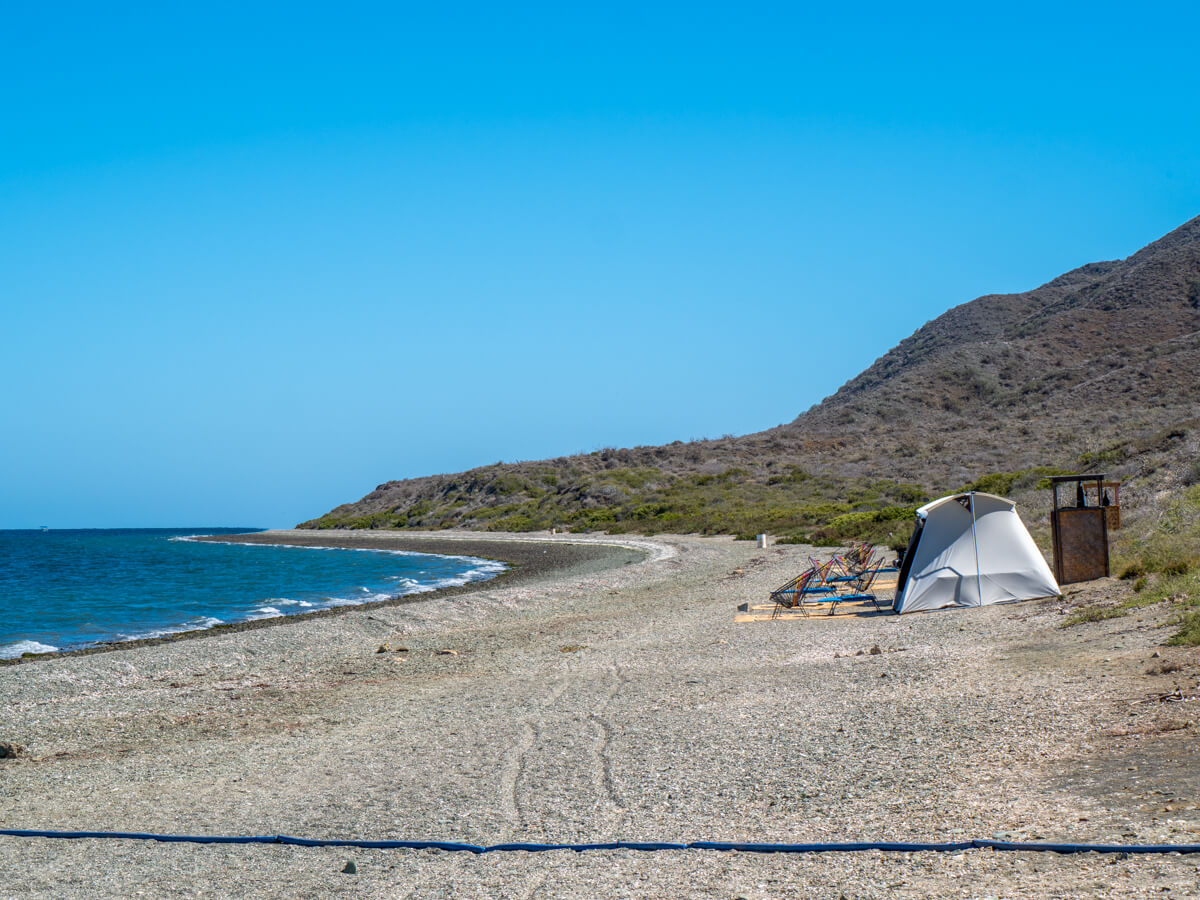 Glamping tents on the beach at Magdalena Bay. The sea is clm and the sky is cloudless.