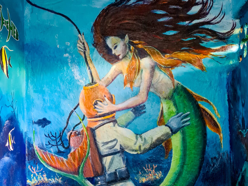 A mural of a mermaid and a SCUBA diver painted on the side of a building in La Paz.
