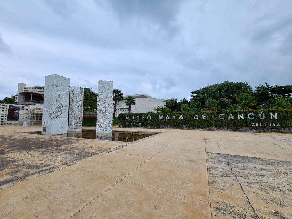 The entrance to Museo Maya de Cancun marked by stone sculptures.