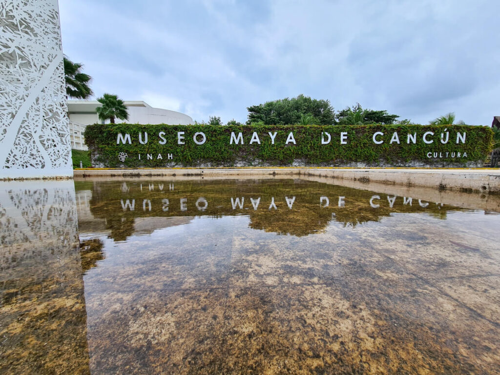 A white sign reading "Museum Maya de Cancun" marking the entrance to the Mayan Museum in Cancun.