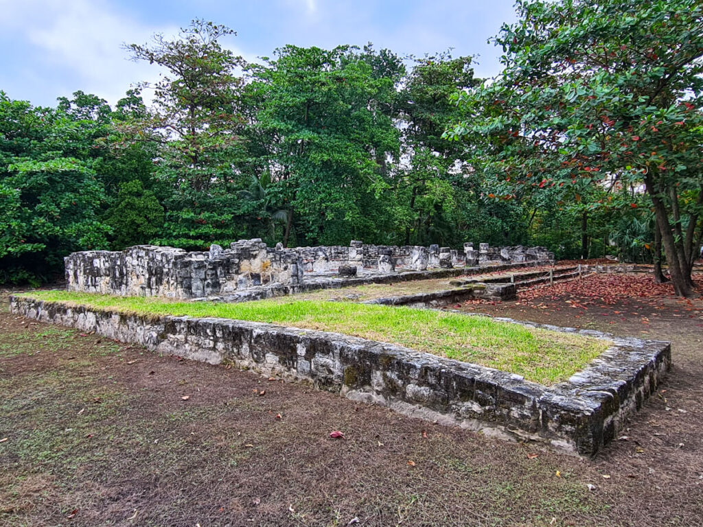 The remains of a large Mayan building at Museo Maya de Cancún. Grass has begun to grow on the  top of the structure.