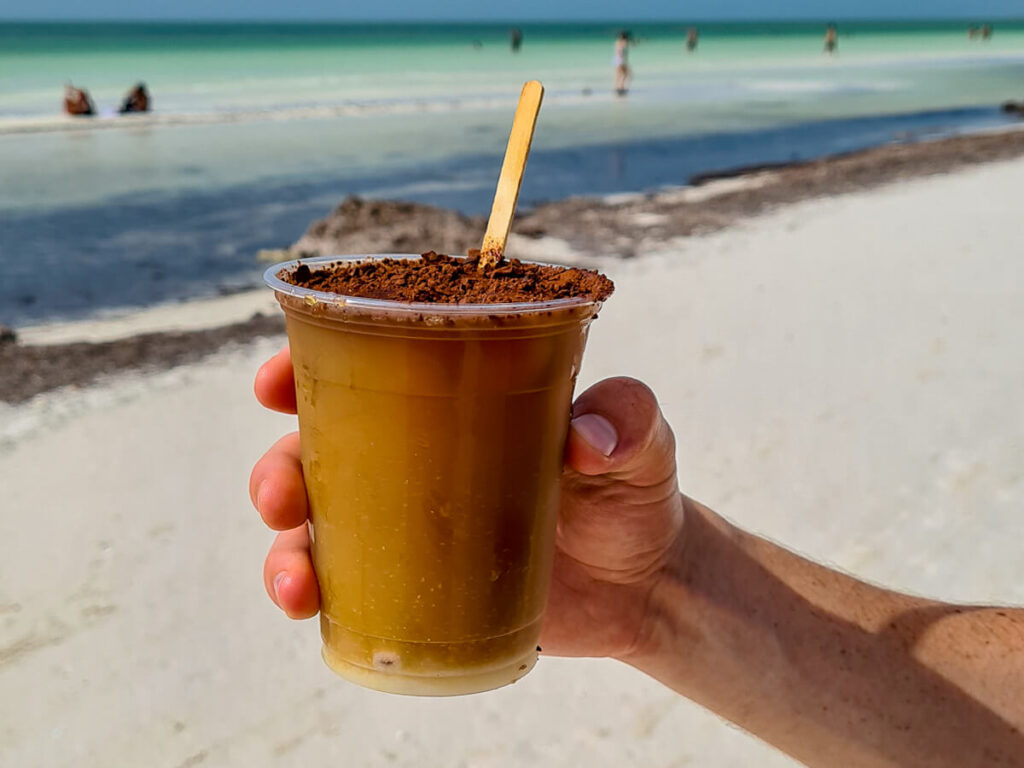 A hand holding a cup of cold brew coffee made by a local vendor on Playa Holbox.