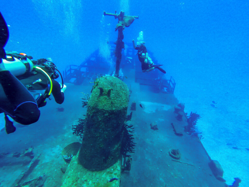 Divers swimming down to a shipwreck in Isla Cozumel.