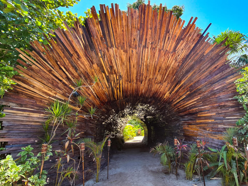 An aesthetic wooden sculpture marking the entrance to an eco-resort in Tulum's Hotel Zone.