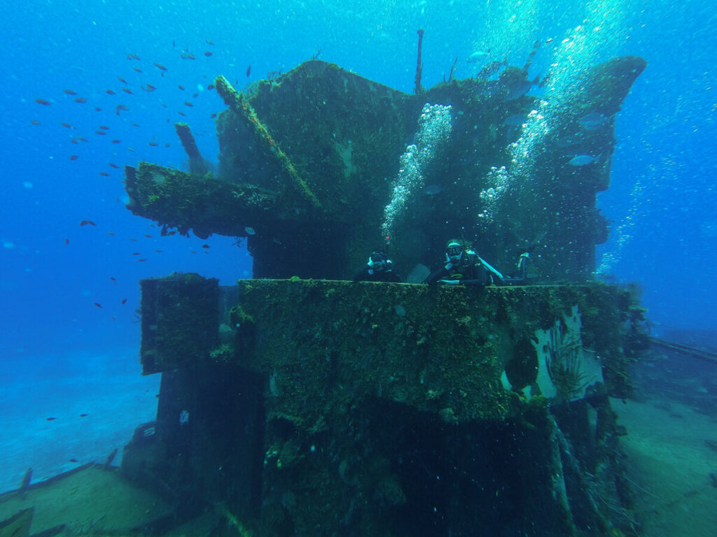 Lucy and Dan posing with a shipwreck while diving in Cozumel.